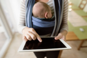 woman with baby uses iPad