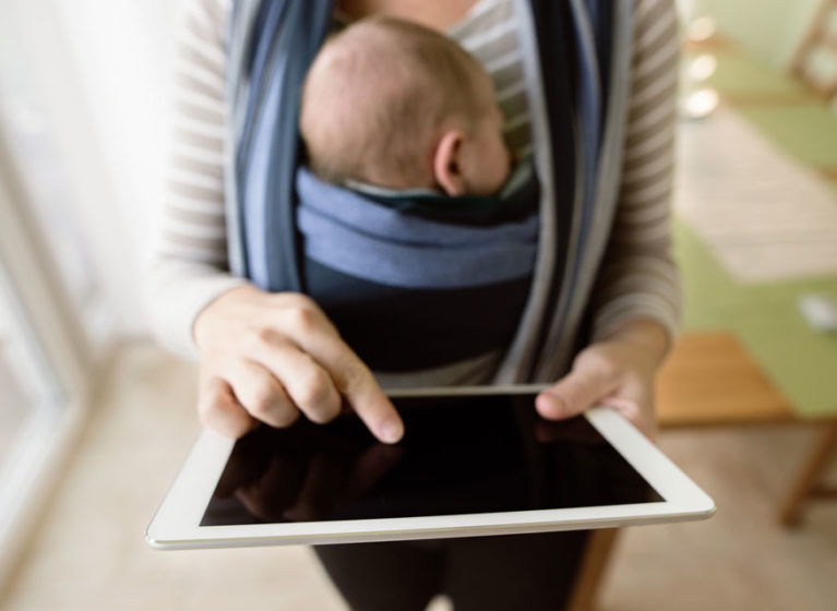 woman with baby uses iPad