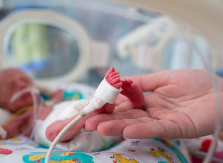 Doctor holds NICU baby's foot with monitor attached