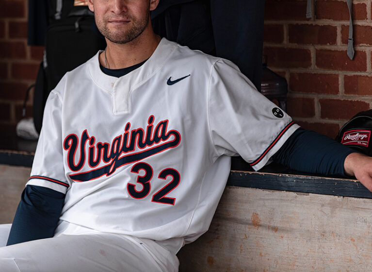 A UVA baseball player sits on a bench