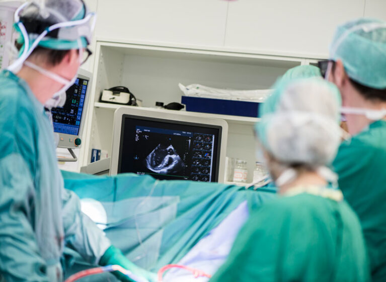 Three clinicians looking at a screen with a cardiac image on it